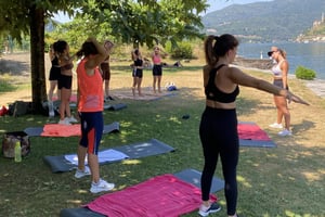 Gruppo di ragazze con tappetini di yoga fanno workout in riva al lago