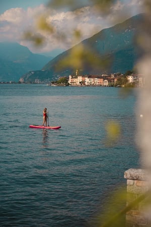 Une jeune fille en maillot de bain rouge traverse le lac sur son stand-up-paddle